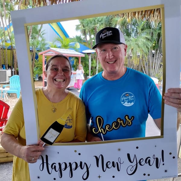 Two smiling people in Mangia Clam Bar shirts pose in a "Happy New Year" frame.